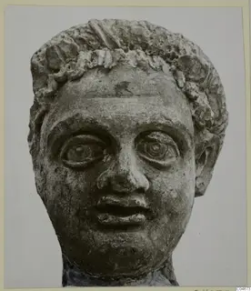 Carved stone head from Mersinaki with curled hair and large, wide-open eyes, seen from the front