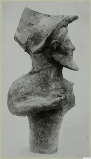 Terracotta figurine from Mersinaki, seen in profile, with a tall cap, folded arms and a cylindrical base