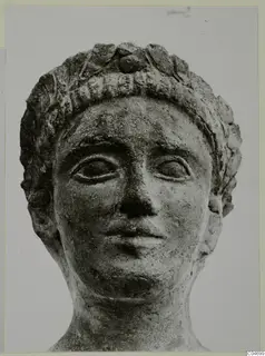 Terracotta Cypro-Greek II: sculpted head wearing a leafy wreath, shown from the front.