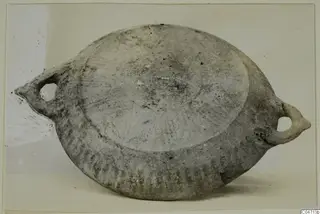Flattened pottery vessel with two loop handles, from Amathus, photographed on a light background