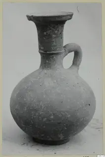 Round-bodied jug with a tall flared neck and strap handle, shown against a pale background