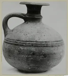 Round-bodied jug with a single handle, a flat-rimmed mouth and two dark bands around the shoulder, photographed against a plain background.