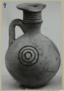 Jug with a round body, a loop handle, banded neck and concentric circles painted on the body.