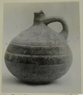 Pottery Bichrome IV jug with a broken neck, a strap handle and horizontal bands around the body, seen from the side
