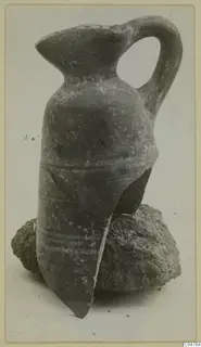 Pottery juglet with a strap handle, leaning on a lump of soil, from Amathus