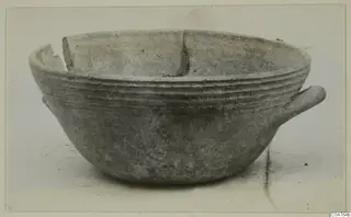 Pottery bowl with ridged rim grooves and a short horizontal handle on the right, broken at the rim