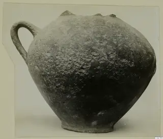 Round one-handled pottery vessel with a dark, pitted surface, from the Amathus tomb finds