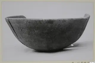 Plain pottery bowl with a rounded body and uneven rim, seen from the side.