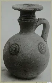 Pottery White Painted IV jug with a round body, strap handle and two concentric-circle motifs