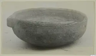 Grey bowl with a small projecting handle on the left and a raised band around the outside below the rim.