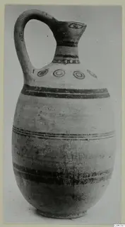 Painted pottery jug with a loop handle, dark bands and a row of concentric circles on the shoulder