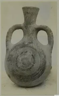 Grey-surfaced two-handled jug with a spiral pattern painted on its body, photographed against a pale backdrop.
