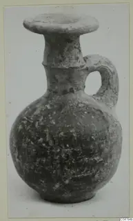 Grey Polished Ware jug with a flaring rim and a single loop handle