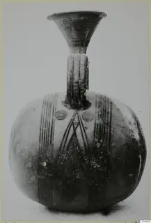 Painted pottery vessel with a flaring neck and ribbed strap handle, with vertical bands and concentric circles in dark paint