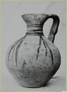 Pottery jug with a single handle, dark painted bands on the neck and shoulder, and long strokes down the body