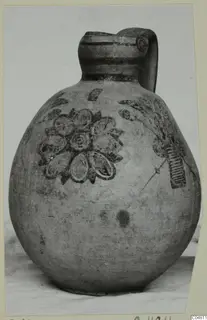 Jug with a strap handle and painted petal and leaf motifs, photographed on a card mount