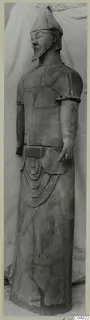 Terracotta Proto-Cypriote I, a standing bearded statue wearing a conical cap, photographed full length against a cloth backdrop.