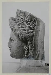 Carved stone head of a woman in profile facing left, with an elaborate layered headdress, from Arsos.