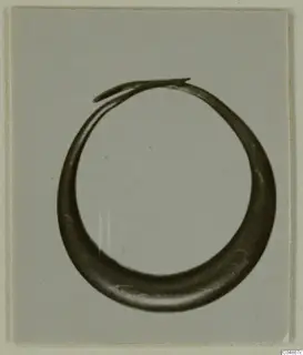 Hoop-shaped metal earring from Enkomi, thick at the base and tapering to overlapping ends at the top