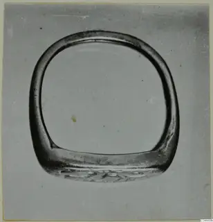 Finger ring from Enkomi with a wide flat bezel, photographed face-on against a plain grey background