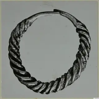 Twisted metal ring with a plain-ended gap, photographed against a grey background.