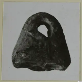 Dark stone seal from Enkomi with a hole pierced through its upper part, photographed on a light card