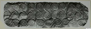 Embossed thin metal sheet with rows of spiral and S-scroll patterns, torn at the edges.