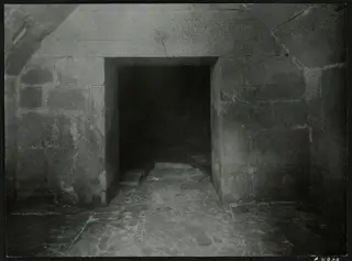 Interior of Tomb 2 at Amathus, looking through a stone-framed doorway into the dark chamber beyond.