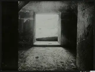 Interior of a stone chamber at Amathus, looking out through a square doorway to bright ground beyond.
