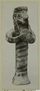 Clay figurine from Amathus with dark painted bands on its body and arms bent across the chest.