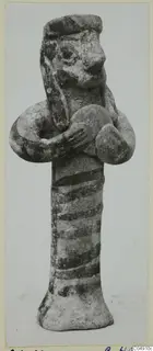 Terracotta figurine of a standing figure with a cap-like head, arms bent at the chest and dark painted bands on the body.
