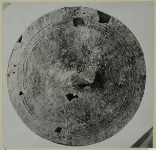 Round bronze object with concentric raised rings, a perforated rim and broken areas, from Idalion