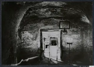 Vaulted interior at Panagia Faneromeni, Kition, with a cloth-draped structure in the doorway and a lit candle stand.