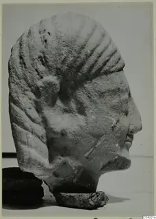 Limestone head from Kition in profile facing right, with ridged hair and a small stone base