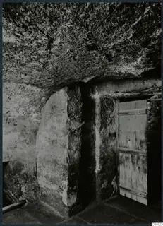 Interior of a built tomb chamber with a wooden door set into the stone wall