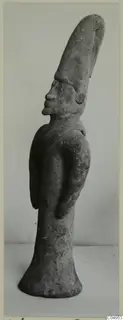 Terracotta figurine of a standing figure with a tall, tapering headdress, shown in profile against a plain background