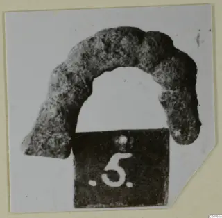 Curved, corroded metal personal adornment from Amathus, shown with a number label.