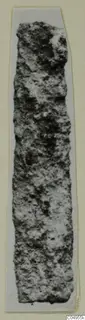 Long, narrow, corroded iron object from Amathus, shown on a pale card strip.