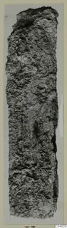 Long, narrow corroded iron object from Amathus, upright, with a rough crusted surface