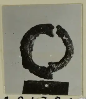 Corroded bronze ring or bracelet, broken open, photographed on a dark block; from Amathus.