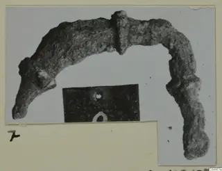 Corroded bronze arched object from Amathus tombs, shown on a mounted photograph card