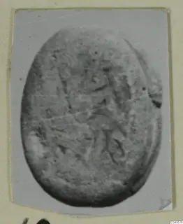 Oval engraved seal or gem from Amathus, shown in a close-up photograph with a faint carved design.