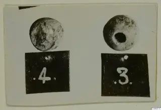 Two round beads, each standing above a black number label; the right bead has a large hole through its centre