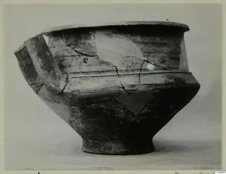 Pottery vessel from Milia with a wide flat rim, a ribbed shoulder and a strap handle, seen from the side