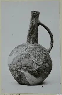 Black Slip Ware jug from Milia with a tall narrow neck and a single loop handle, decorated with linear bands
