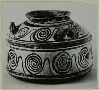 Black-painted pottery vessel with a wide flaring rim, a small handle and bands of spirals around the body.