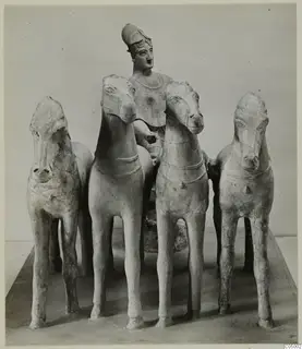 Terracotta group of four horses with a helmeted figure standing behind them