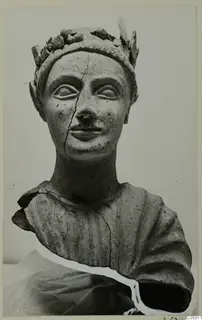 Terracotta bust of a figure wearing a leafy wreath, with a crack running down the face and neck