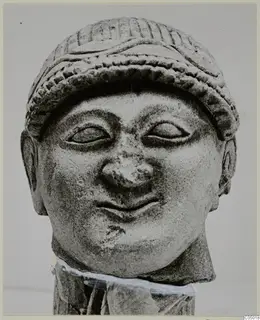 Limestone head and upper neck from Mersinaki, wearing a ridged cap, with a broken nose and a slight smile