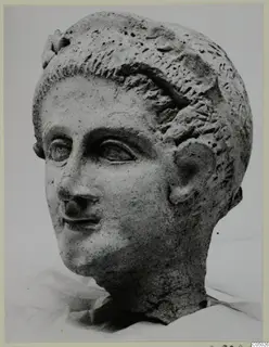 Head of a sculpture from Mersinaki, a male or youthful face with short hair, shown in a photograph against a pale background.